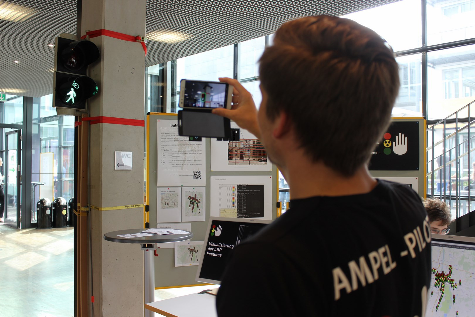 Foto des Projekttags: Ein Student hält sein Smartphone mit der Ampel-Pilot App in Richtung einer Fußgängerampel.